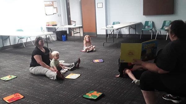 small children sitting on floor being read a story book
