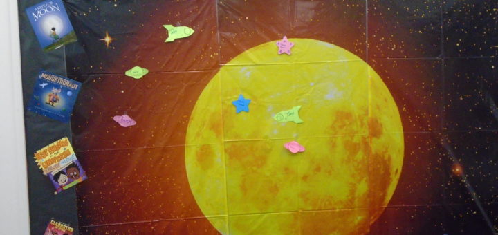 Bulletin Board background of a big yellow moon, and sign that says A Universe of Stories