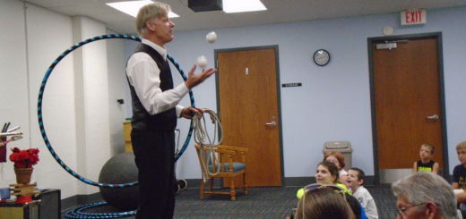 Man in vest holding hula hoop and juggling 3 balls