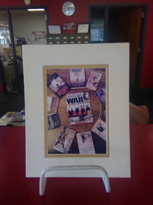 Photo of a circle of books on a wooden backround. One book is featured in the center of the circle.