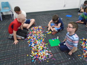 4 children sitting around a pile of Legos