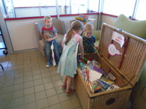 3 children choosing toys from wicker chest
