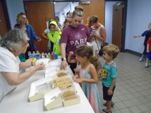 line of small children taking cookies off a table